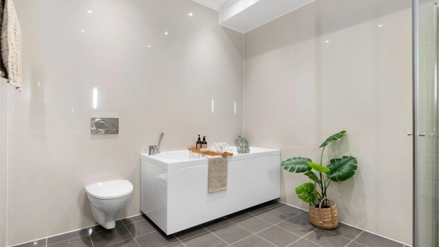 Badet er helfliset med gulvvarme og innredet med baderomsmøbler med dobbel vask, vegghengt wc og både dusjhjørne og badekar