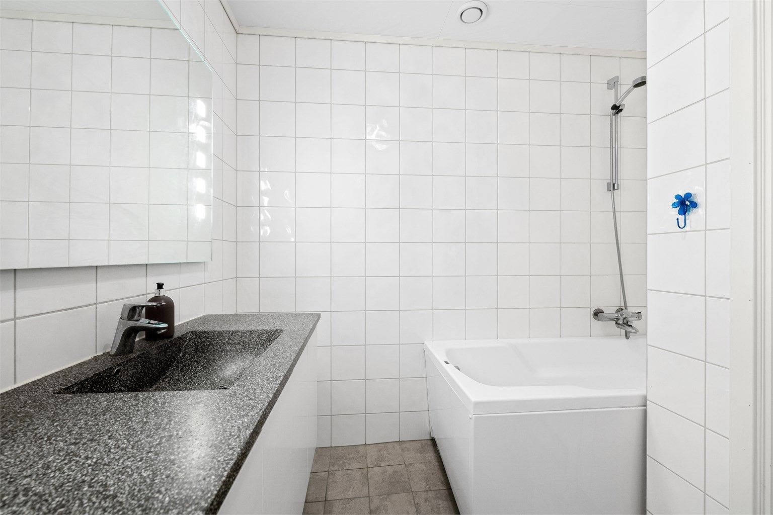 Badet er utstyrt med badekar i en egen dusjnisje.