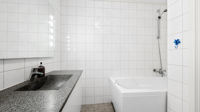 Badet er utstyrt med badekar i en egen dusjnisje.