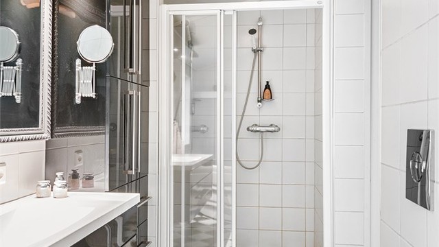 Innredningen inkluderer vegghengt toalett, servant med overlys og et praktisk høyskap for oppbevaring.