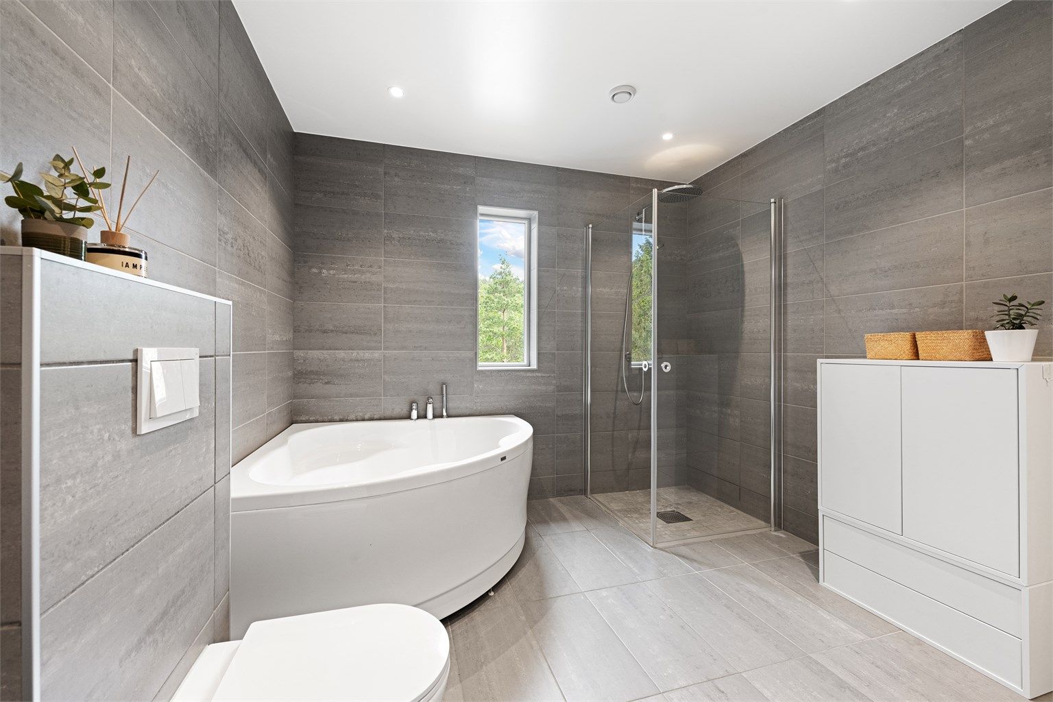 Badet har både hjørnebadekar og en separat dusjnisje med glassdører