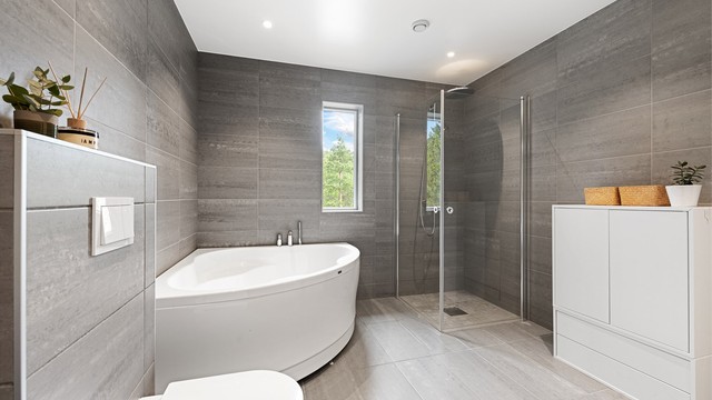 Badet har både hjørnebadekar og en separat dusjnisje med glassdører