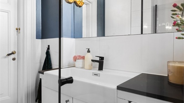Badet er utstyrt med vegghengt toalett og dusjhjørne med innfellbare glassdører.