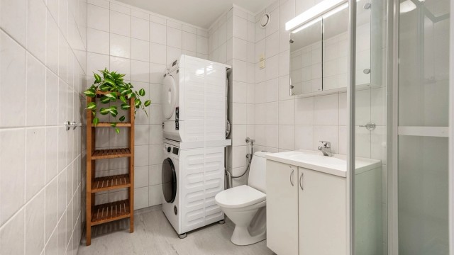 Badet har flislagte vegger, dusjkabinett og servantinnredning.