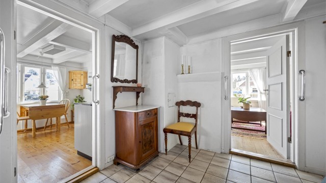 Fra gangen er det adkomst til kjøkken og stue. De synlige takbjelkene er et gjennomgående element i boligens eldre del.