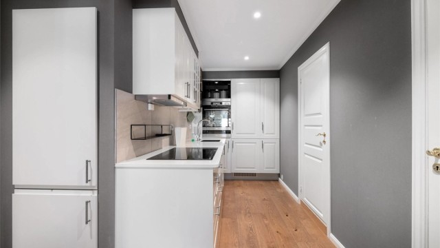 Kjøkkeninnredning med hvite profilerte fronter fra 2015 og benkeplate av laminat. Det er integrert 2 stk. kjøl/fryseskap, oppvaskmaskin og induksjonstopp. Komfyrvakt. Det er laget plass til integrert komfyr etc. Kjøkkenventilator med avtrekk ut.