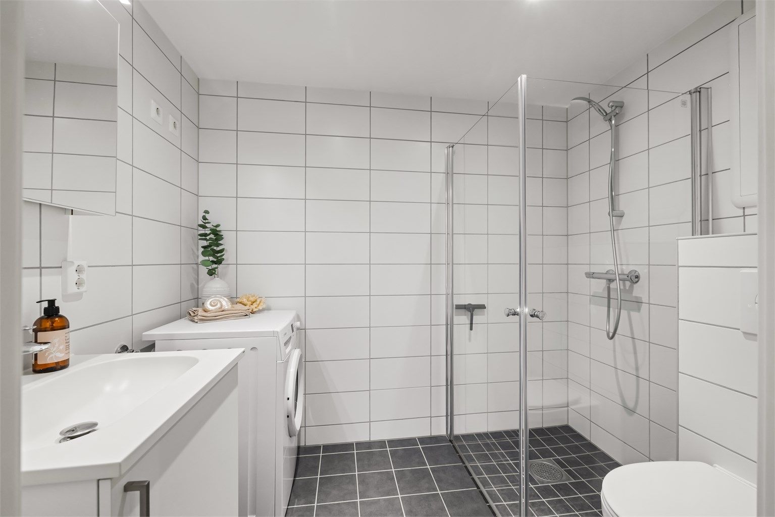 Delikat, flislagt bad med varme i gulvet og opplegg for vaskemaskin.