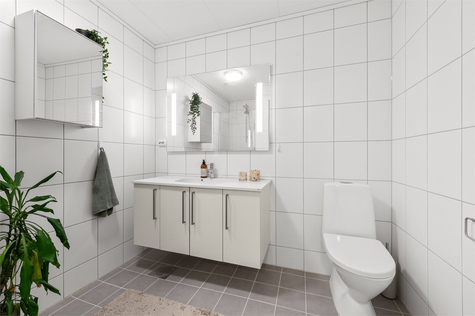 Helfliset bad i første etasje, utstyrt med gulvvarme, vegghengt servantinnredning og dusjnisje med glassdør.