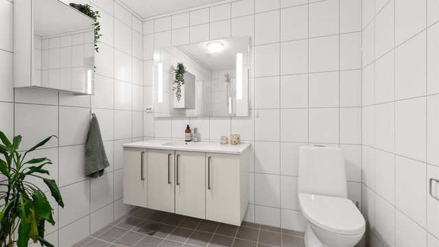 Helfliset bad i første etasje, utstyrt med gulvvarme, vegghengt servantinnredning og dusjnisje med glassdør.