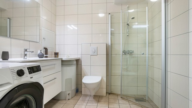 Flislagt bad med gulvvarme, dusjhjørne med innfellbare glassdører og opplegg for vaskemaskin.