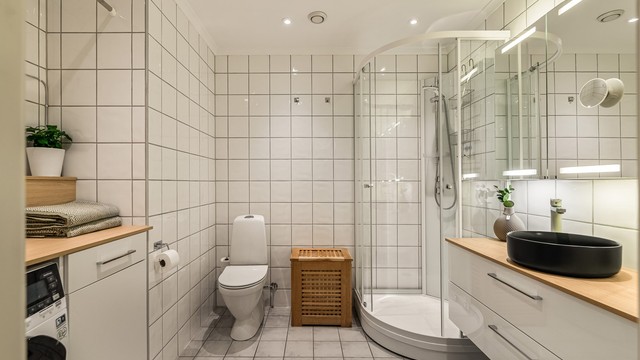 Dusjkabinett med glassvegger, gulvstående toalett og innfelte downlights i himling.