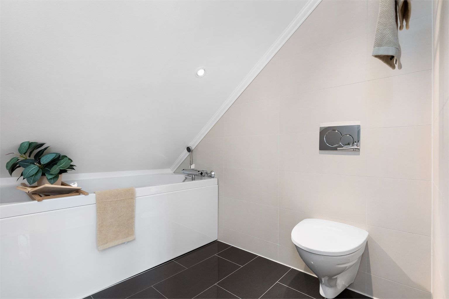 Badet er helfliset med varmekabler og innredet med baderomsmøbel, badekar og vegghengt wc