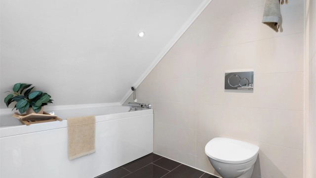Badet er helfliset med varmekabler og innredet med baderomsmøbel, badekar og vegghengt wc