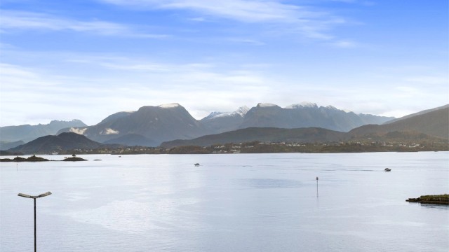 Åpent fjordlandskap med fjellene på Sunnmøre i bakgrunnen.