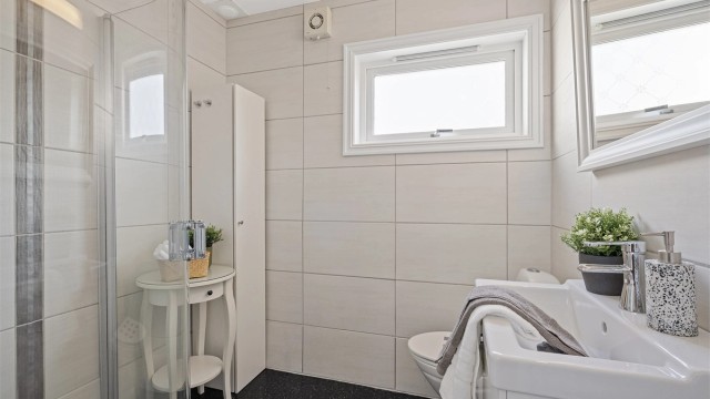 Fint bad som var nytt i 2005. Badet ble pusset opp av fagfolk og er tidløst med lyse fliser på vegg og belegg på gulv. Vegghengt toalett, dusjhjørne med innfellbare dører og servant med skuffer. Speil på vegg.