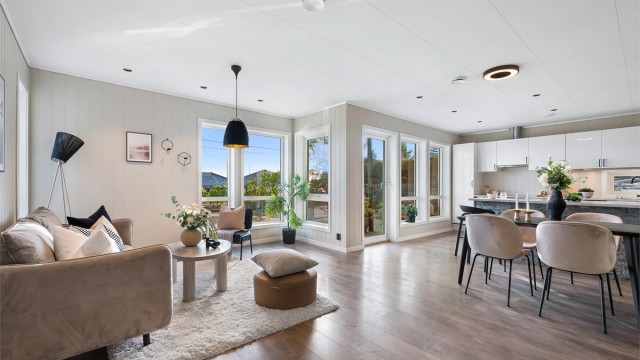 Lys og moderne stue med åpen løsning mot kjøkken og spiseplass og store vindusflater som gir flott romfølelse og godt lysinnslipp