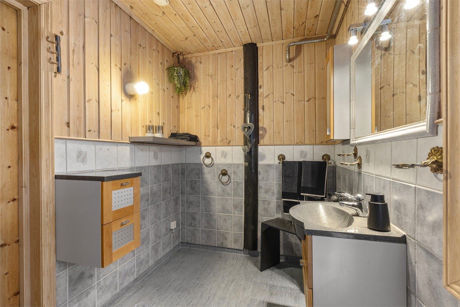 Badet innredet med servant, dusjkabinett, toalett fra 2005 og det er opplegg for vaskemaskin.