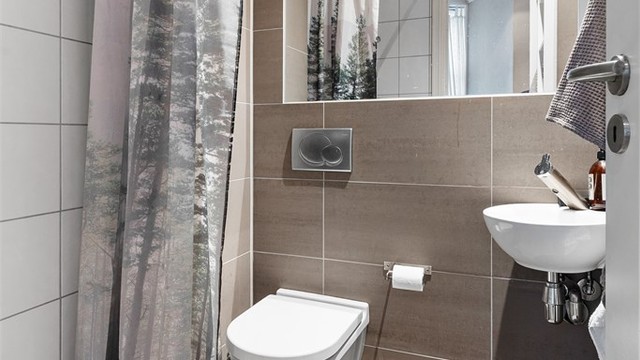 Badet i hybelen er fra 2009. Flislagt gulv med gulvvarme og flislagte vegger. Nedsenket himling med downlights. Vegghengt servant med ett-greps armatur. Speil med overlys. Dusjhjørne med forheng. Vegghengt dusjarmatur. Vegghengt toalett.