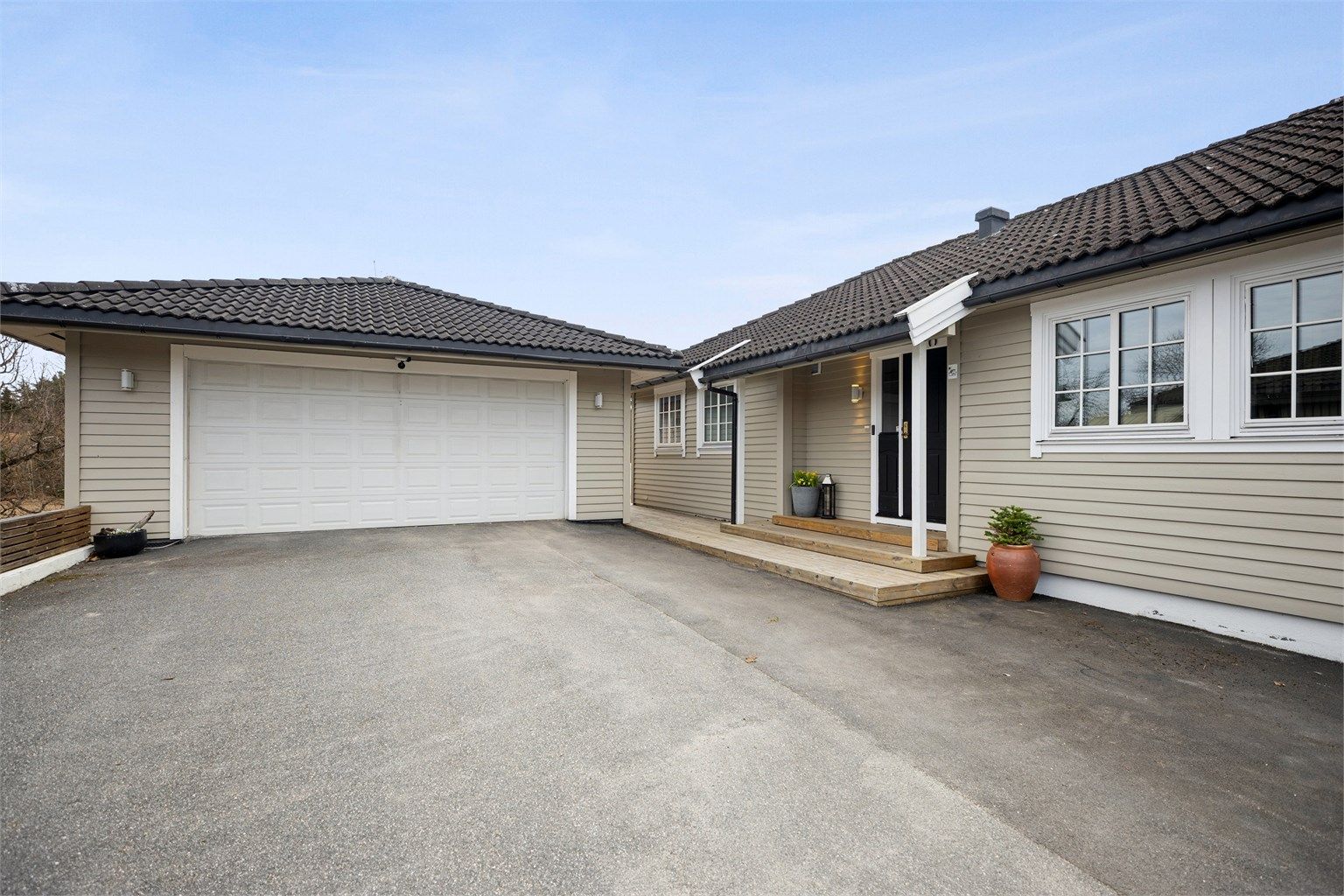 Praktisk asfaltert gårdsplass med enkel adkomst til dobbel garasje og et innbydende inngangsparti. Her får du god plass til parkering og en ryddig, lettstelt adkomst til boligen