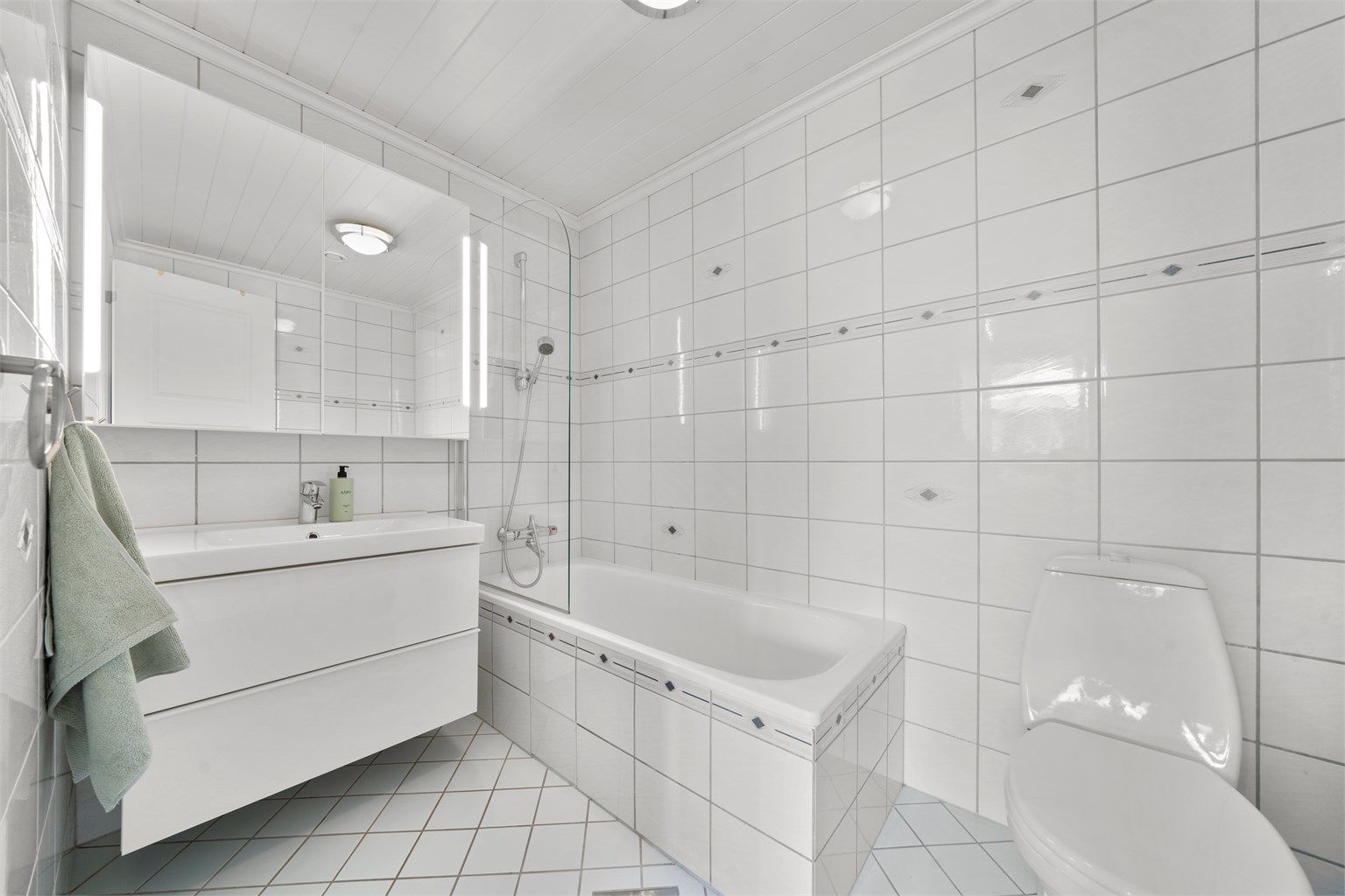 Flislagt badekar med glassfelt. Vegghengt speilskap med innebygd lys. TG3 etter helhetsvurdering.