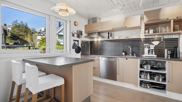 Moderne HTH kjøkkeninnredning fra 2010 med slette fronter og benkeplate av laminat. Her finnes også en praktisk kjøkkenøy for et raskt måltid.