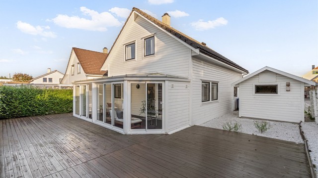 Skjermet uteområde omsluttet av hekk og tilhørende frittstående redskapsbod.
