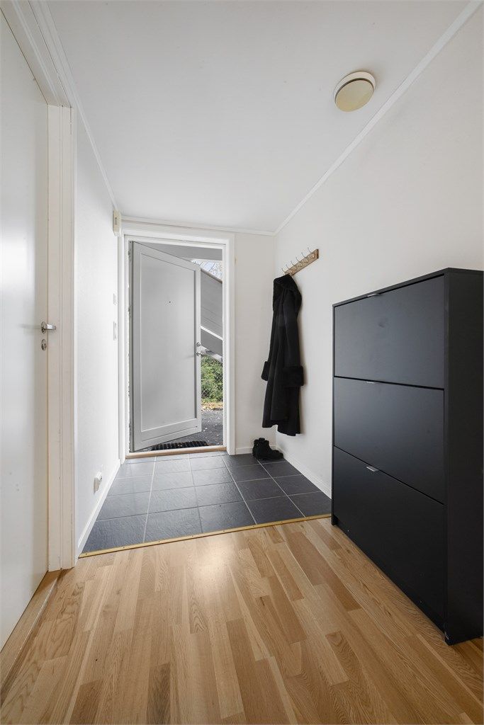 Man kommer inn i en flislagt entré med gulvvarme og knaggrekker for å henge av seg ytterklær