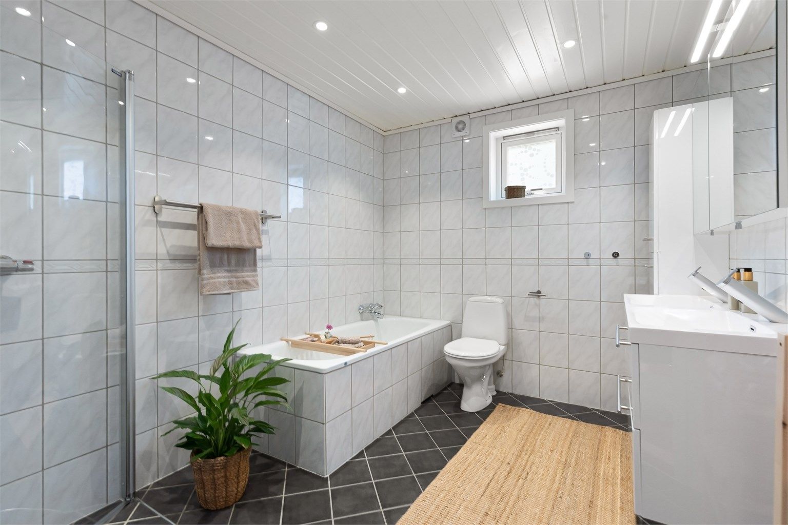 Pent flislagt baderom med både dusj og badekar og gode oppbevaringsmuligheter