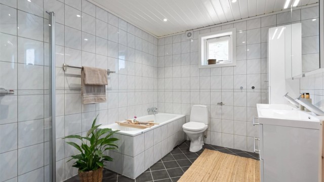 Pent flislagt baderom med både dusj og badekar og gode oppbevaringsmuligheter