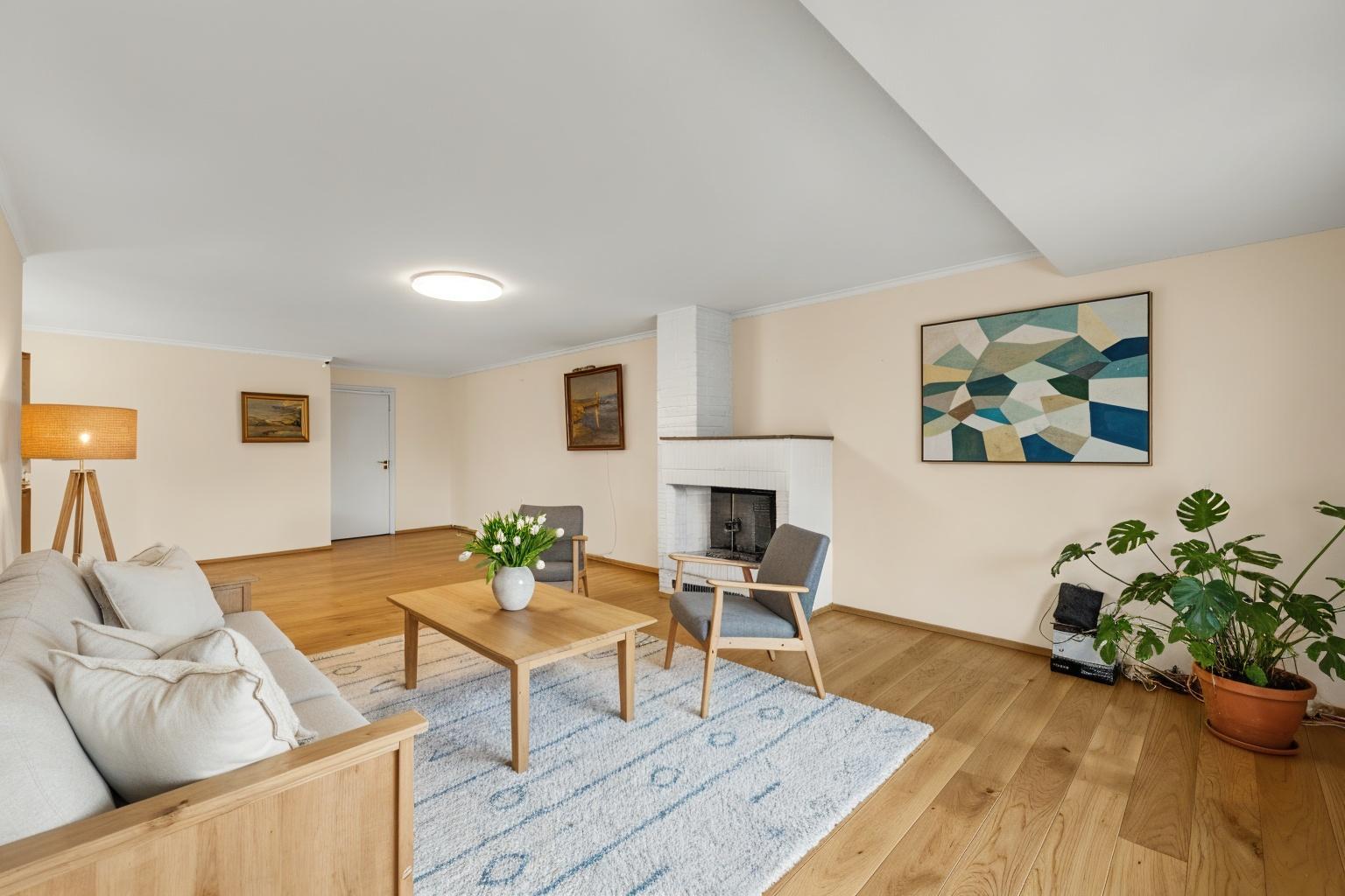 Stuen er romslig og møbleringsvennlig og med en hyggelig peis som varmer opp og skaper hygge på kjøligere dager. Digitalt stylet bilde.