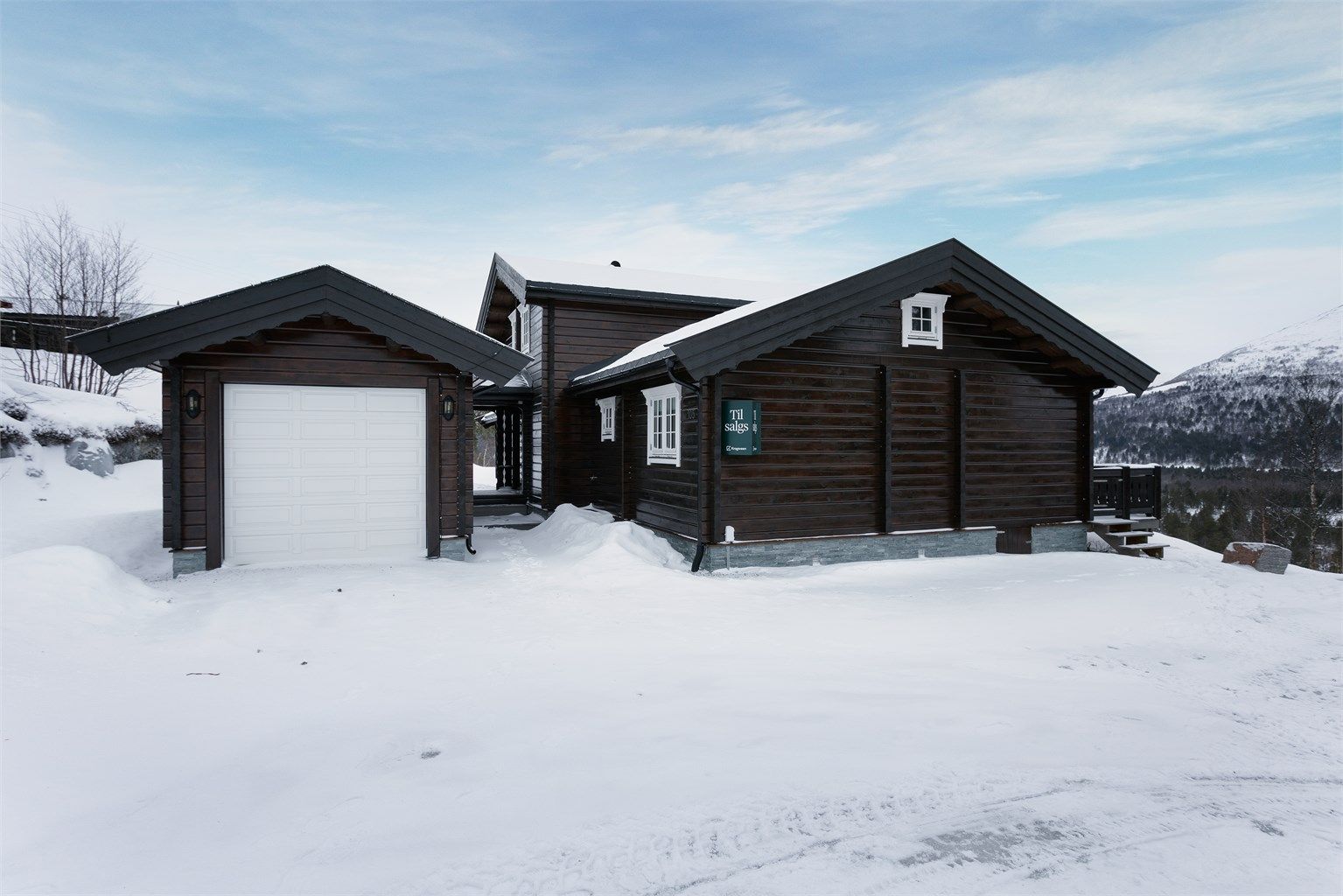 Adkomst, fasade og stort parkeringsareal i tilknytning til hytten