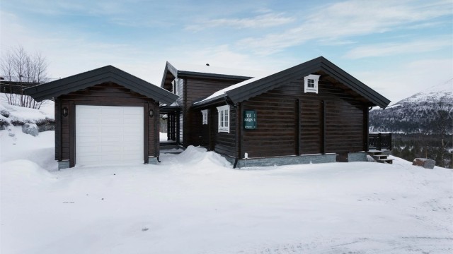 Adkomst, fasade og stort parkeringsareal i tilknytning til hytten