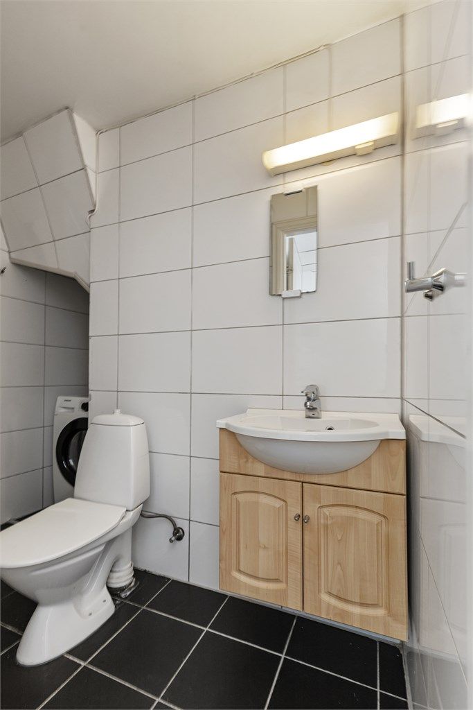 Badet har fliser på gulv og vegger, og er utstyrt med dusjhjørne og opplegg for vaskemaskin.