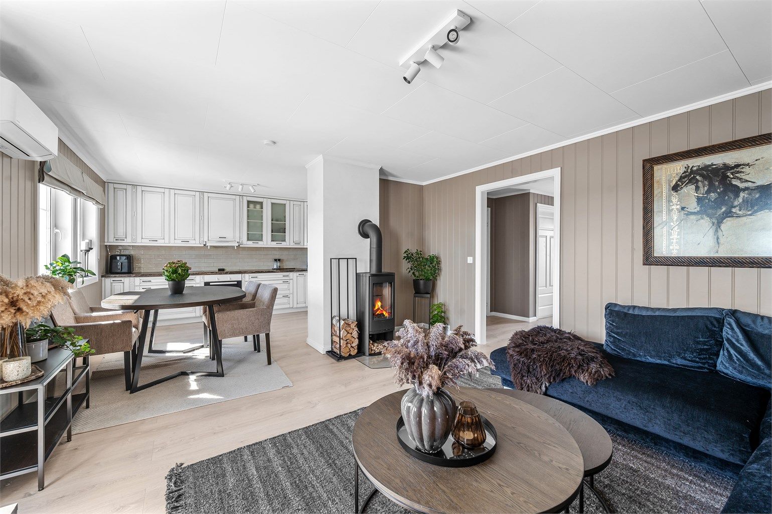 Stuen har en åpen løsning mot kjøkkenet, med både peisovn og varmepumpe for effektiv oppvarming. Det er nyere gulv i stue, kjøkken og gang.
