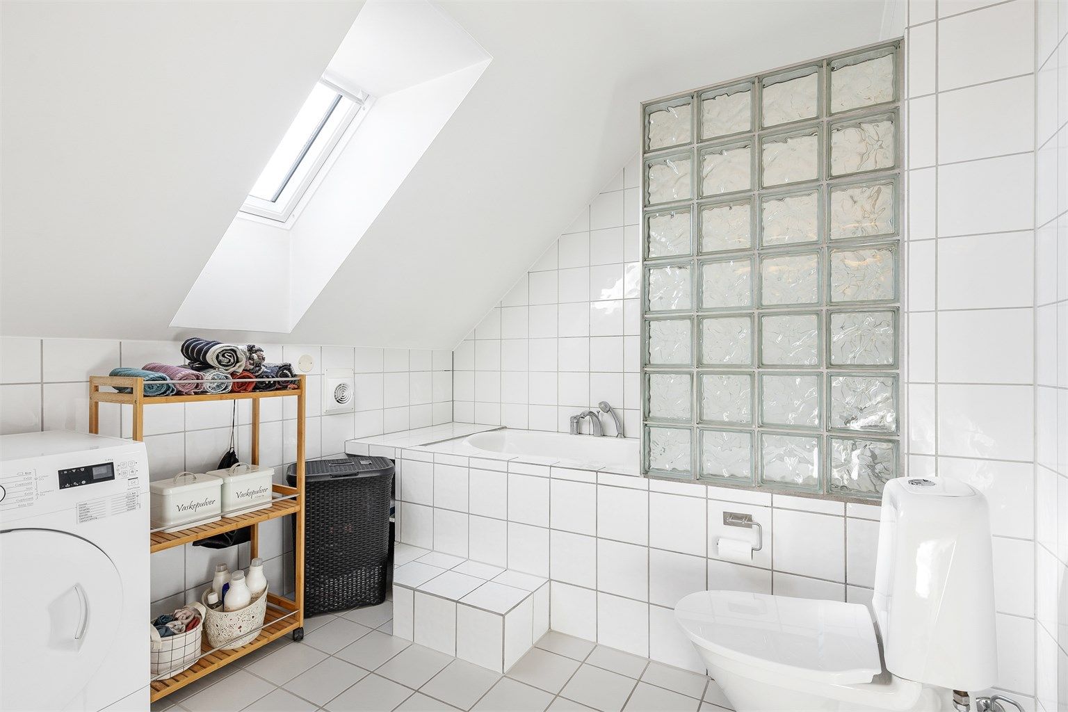 Badekar med vegghengt armatur. Gulvstående toalett. Mekanisk avtrekksvifte i vegg.