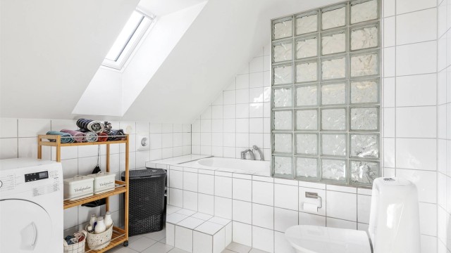 Badekar med vegghengt armatur. Gulvstående toalett. Mekanisk avtrekksvifte i vegg.