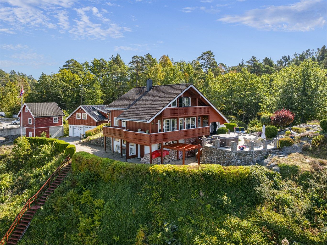 Eneboligen sett fra sjøsiden, med balkong og stor terrasse.