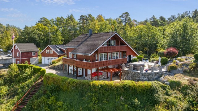 Eneboligen sett fra sjøsiden, med balkong og stor terrasse.