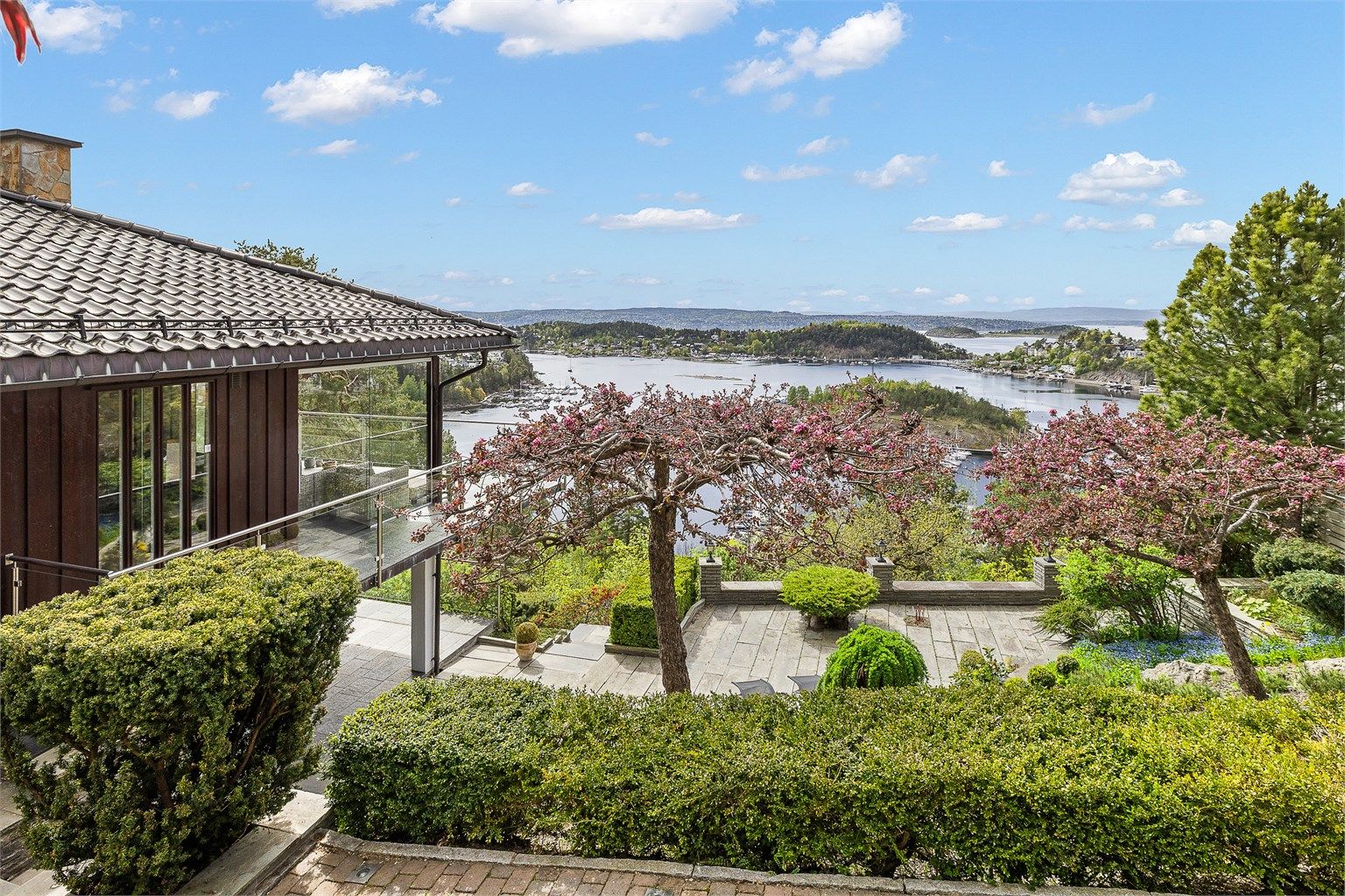 Terrassert tomt som er parkmessig opparbeidet med store skiferbelagte markterrasser, belysning, store bed med prydbusker og et lite flatt plenareal