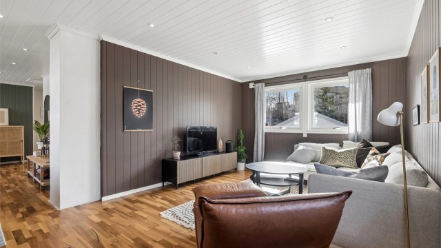 Stuen er romslig og har god plass til både sofagruppe og spiseplass. Rommet oppleves lyst og trivelig, og store vindusflater slipper inn godt med dagslys. (Foto: EFKT v/Jonas Hasselgren)