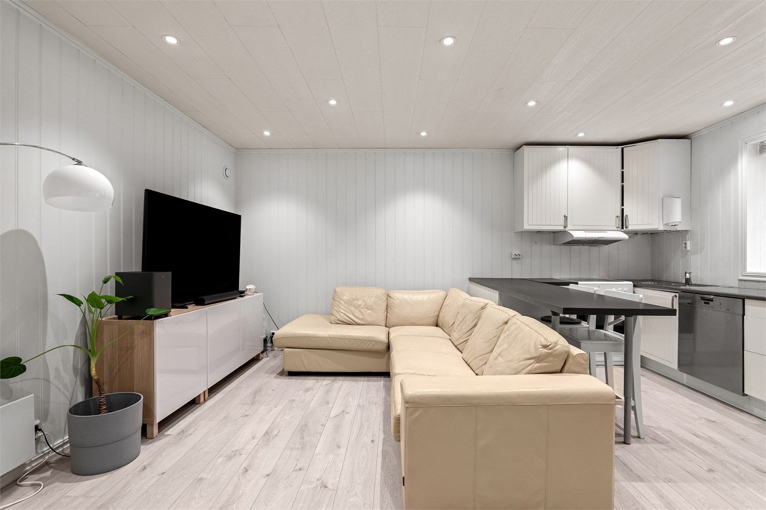 Stuen fremstår lys og innbydende med gjennomgående lyse farger og praktisk planløsning mot kjøkken.