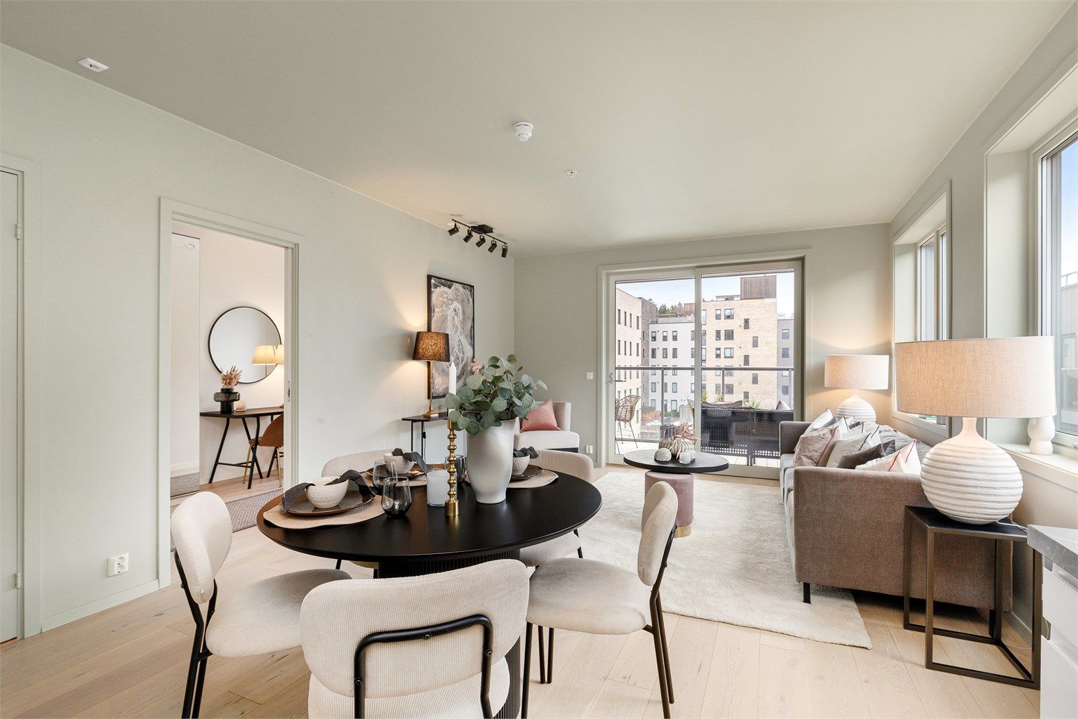 Leilighetens oppholdsrom har åpen løsning mellom stue og kjøkken, samt store vindusflater på flere vegger som gir masse naturlig lys til leiligheten