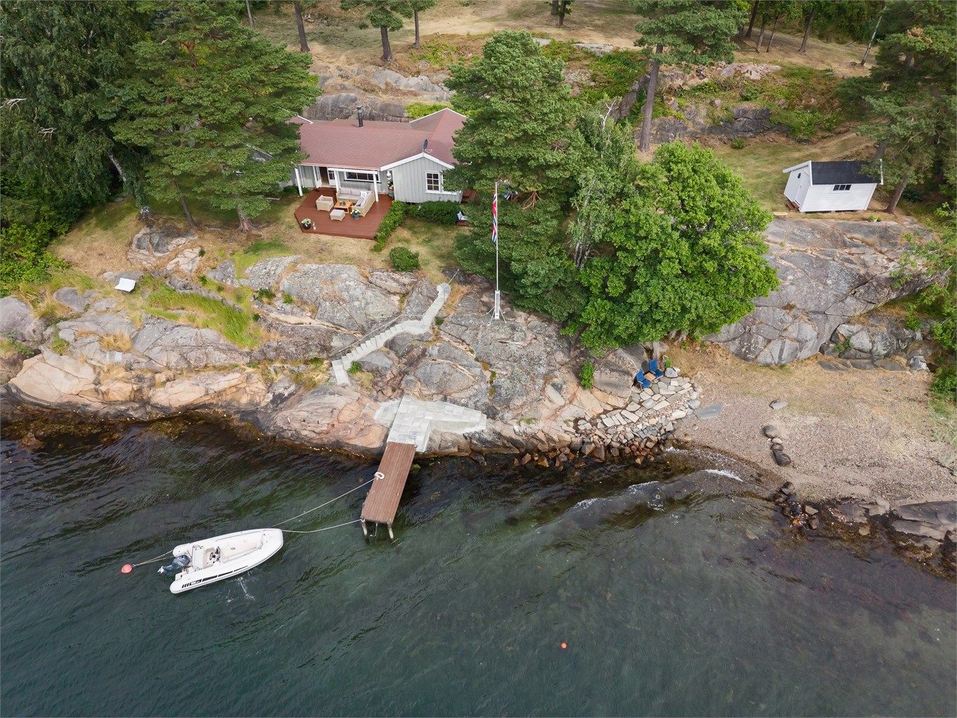 Eiendommen ligger idyllisk til med svaberg og strandlinje.