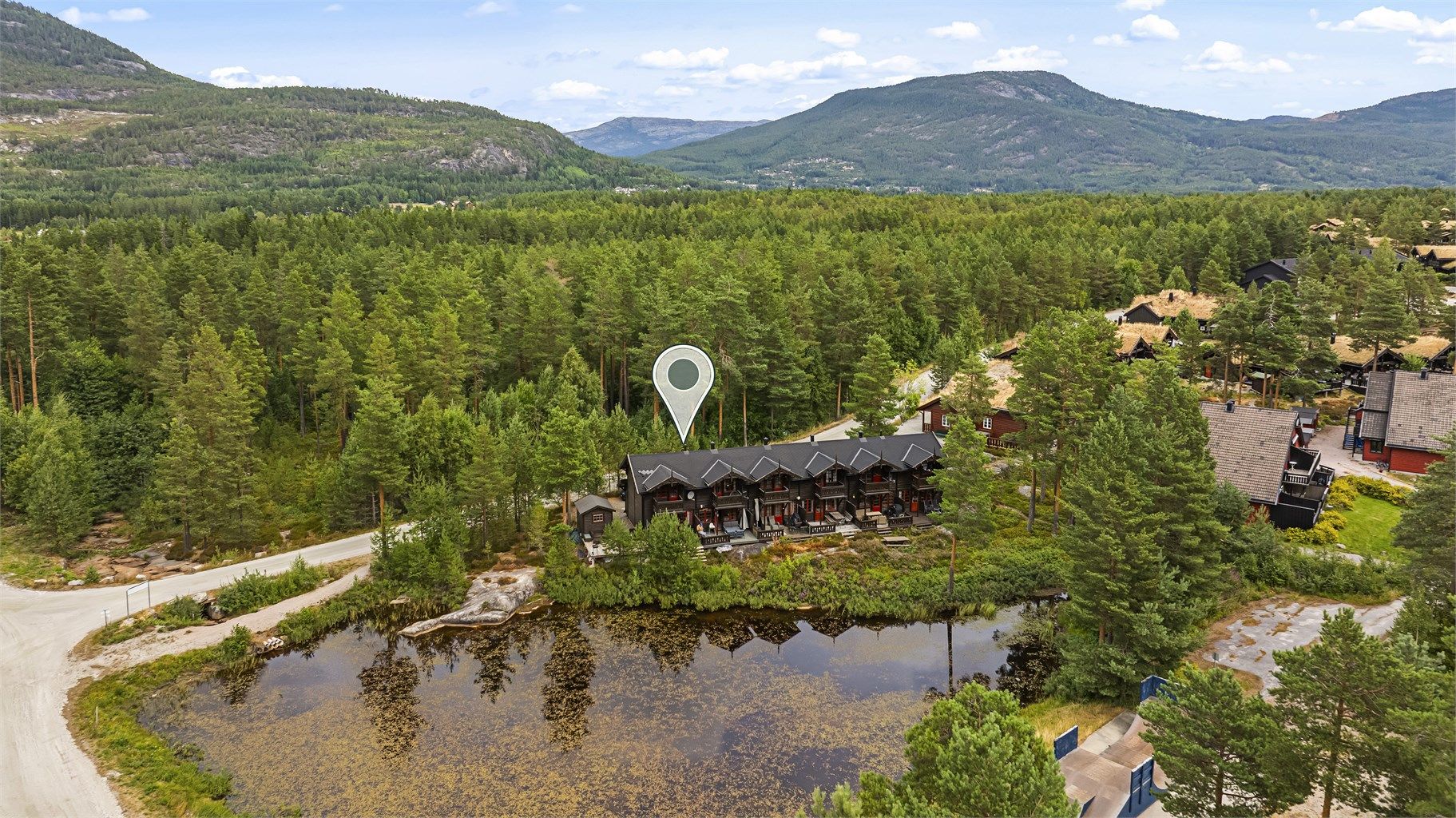 Fritidsboligen ligger idyllisk til ved et lite tjern.