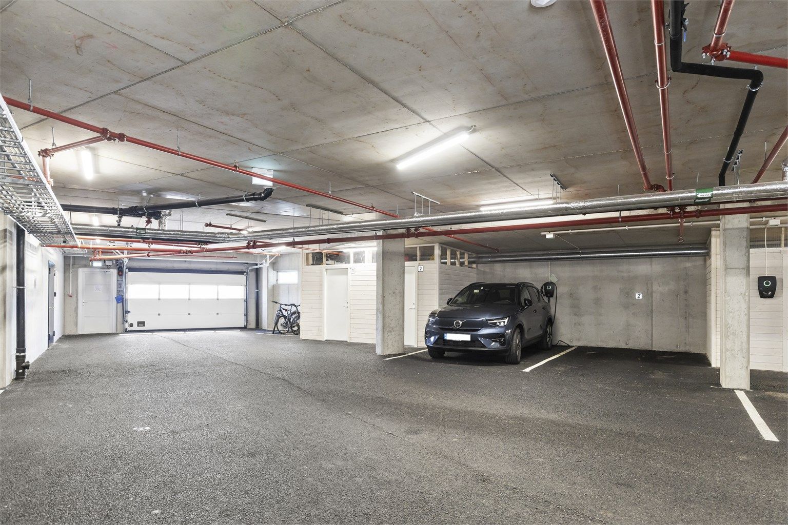 Fast, romslig garasjeplass med tilrettelagt ladepunkt og tilhørende bod.