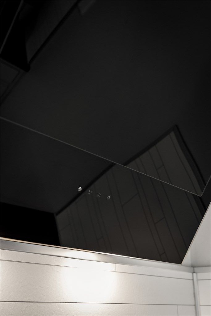 Moderne, vegghengt ventilator over platetoppen.