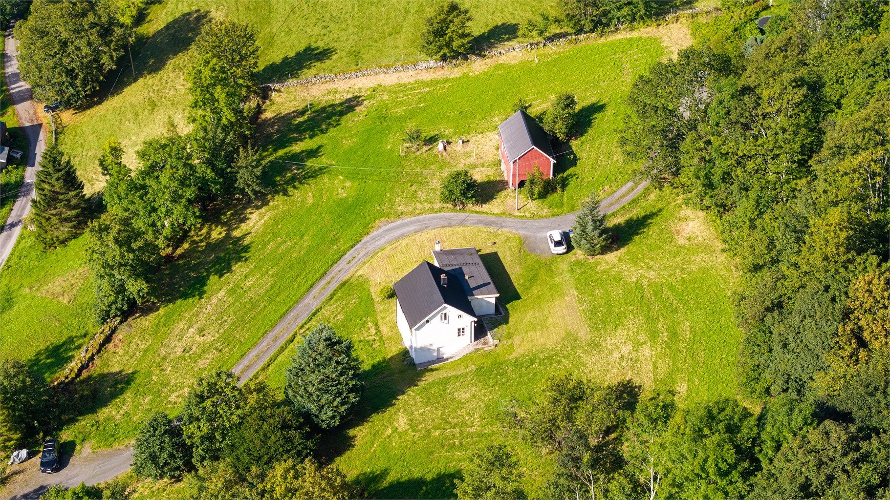 Eiendommen har store grøntarealer som grenser mot skogkledde åssider.