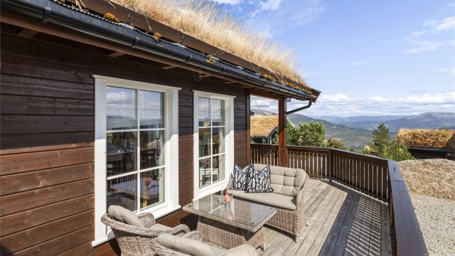 Terrassen er belagt med terrassebord og har rekkverk av tre.