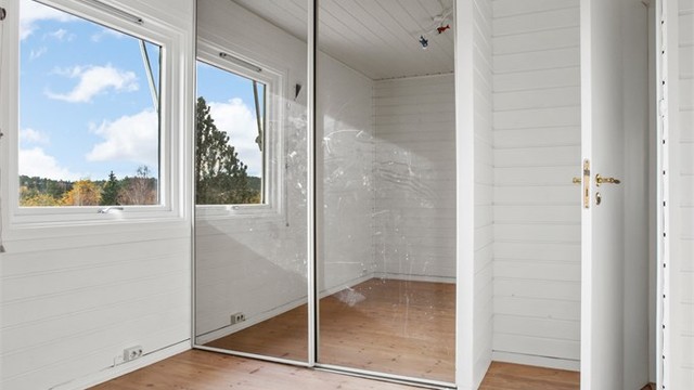 Soverom utstyrt med skyvedørsgarderobe med speildører.