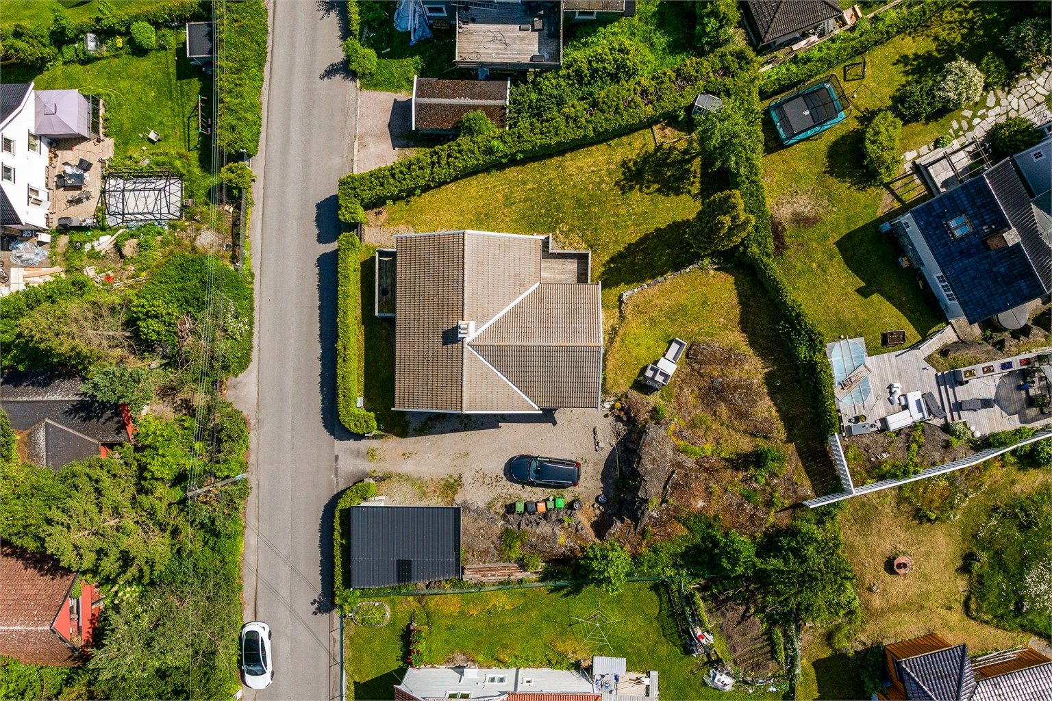 Tomta er opparbeidet med gruslagt gårdsplass på fremsiden av boligen, og stor hage som strekker seg rundt boligen.